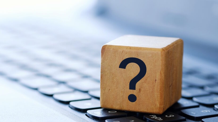 A question mark on a wooden cube on a computer keyboard