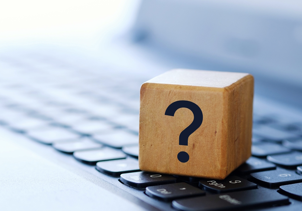 A question mark on a wooden cube on a computer keyboard